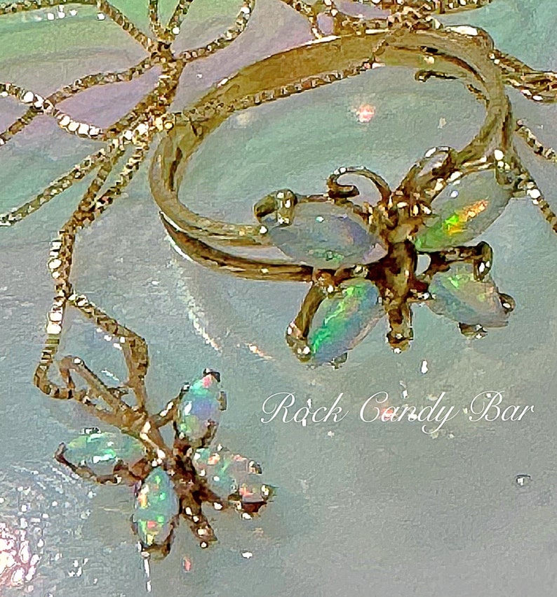 May include: Two gold necklaces with opal butterfly pendants. The necklaces are on a light blue background with the text "Rock Candy Bar".