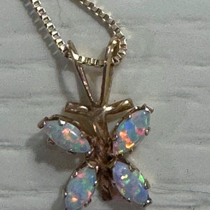 May include: A gold butterfly pendant necklace with five iridescent opal stones. The necklace has a delicate chain.