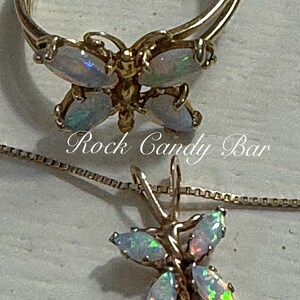 May include: A gold butterfly ring and necklace set with iridescent opal stones. The ring is double-banded and the necklace has a delicate chain.