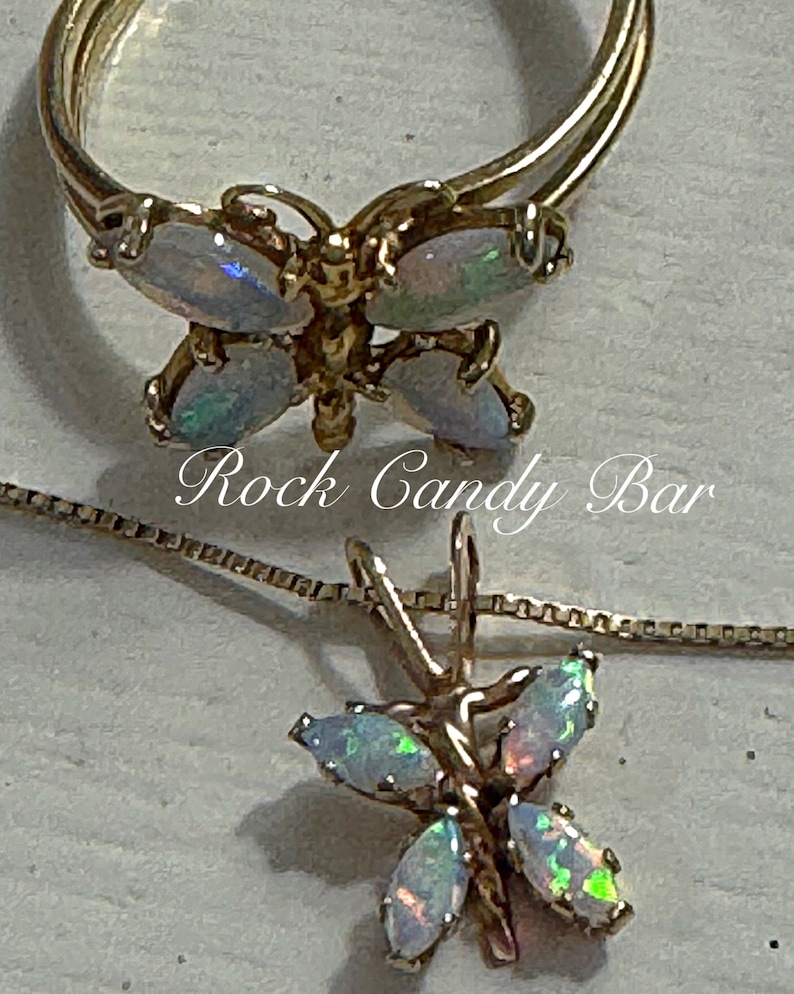May include: A gold butterfly ring and necklace set with iridescent opal stones. The ring is double-banded and the necklace has a delicate chain.