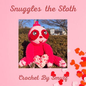 May include: A pink crocheted sloth holding a heart-shaped crocheted object. The sloth has red eyes and a white mouth. The background is a pink surface with red and white hearts scattered around the sloth.