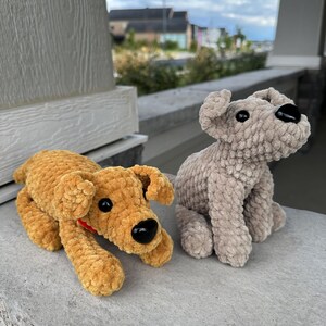May include: Two crocheted plush dog toys. One is brown and the other is gray. Both have black eyes and noses.
