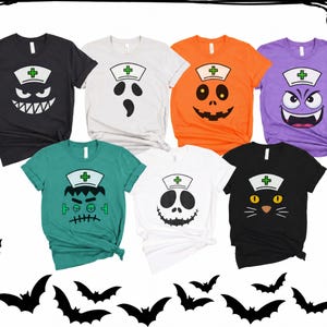 May include: A collection of seven short-sleeved t-shirts in black, white, orange, purple, and teal. Each shirt features a graphic of a different character wearing a white nurse cap with a green cross, including a ghost, pumpkin, and cat.