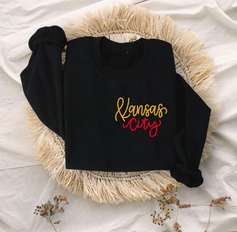 Puede incluir: Sudadera negra con un dise&ntilde;o bordado en dorado y rojo que dice "Kansas City".