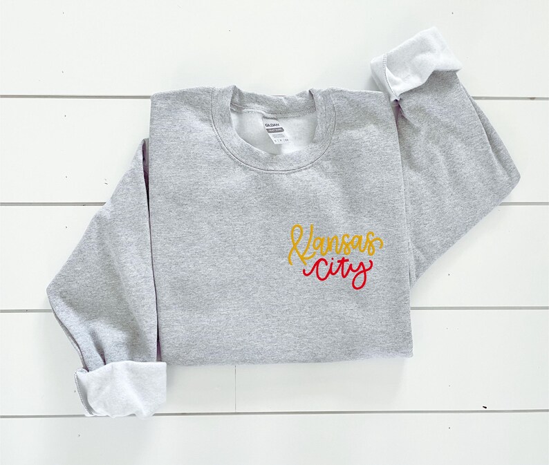 Puede incluir: Sudadera gris con un dise&ntilde;o bordado en amarillo y rojo que dice "Kansas City".