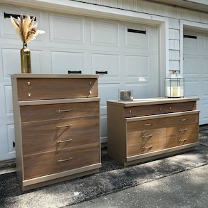 May include: Two wooden dressers with gold hardware. The dresser on the left has six drawers and the dresser on the right has four drawers. Both dressers have a light brown wood finish with a beige base.