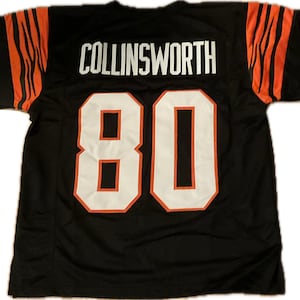 May include: Black football jersey with orange tiger stripes on the sleeves. The back of the jersey has the name "COLLINSWORTH" and the number "80" in white with orange outlines.