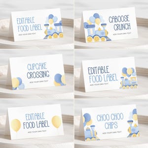 May include: White tent cards with blue and yellow train and balloon illustrations. Text includes "Editable Food Label", "Caboose Crunch", "Cupcake Crossing", and "Choo Choo Chips". Each card has space to add custom text.