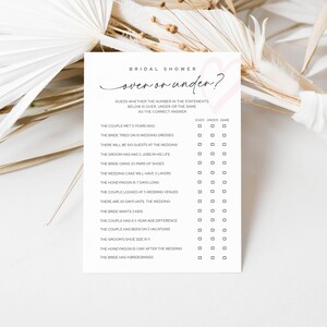 May include: A white bridal shower game card with the text "over or under?" in black script. The card includes a list of statements with check boxes for guests to guess if the number is over, under, or the same.