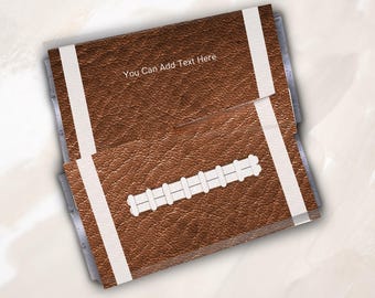 May include: A rectangular brown leather-textured item resembling an American football, featuring white vertical stripes on the ends and white laces in the center. The text "You Can Add Text Here" is printed in white on the upper portion.