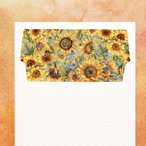 Könnte beinhalten: Ein weißer Umschlag mit einem Aquarell-Sonnenblumen-Design auf der Klappe. Die Klappe zeigt ein lebendiges Muster aus gelben Sonnenblumen, grünen Blättern und blauen Akzenten vor einem hellen Hintergrund. Der Umschlag ist vor einer orange-gelben Aquarellwaschung platziert.