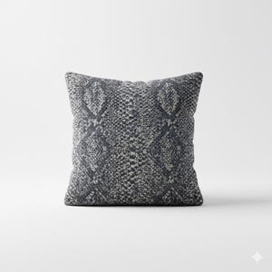Pode incluir: Almofada decorativa quadrada com um padrão de pele de cobra em tons de cinza e preto. A almofada tem uma aparência texturizada e uma paleta de cores neutras, adequada para vários estilos de design de interiores.
