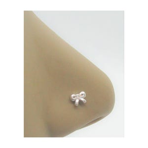 May include: A silver nose ring with a bow design.