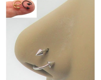 May include: A silver nose ring with two pointed ends. The ring is shown in a close-up view on a person's nose.