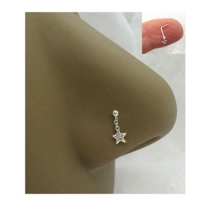 May include: A silver nose ring with a small star charm dangling from a chain. The star has a small clear stone in the center.