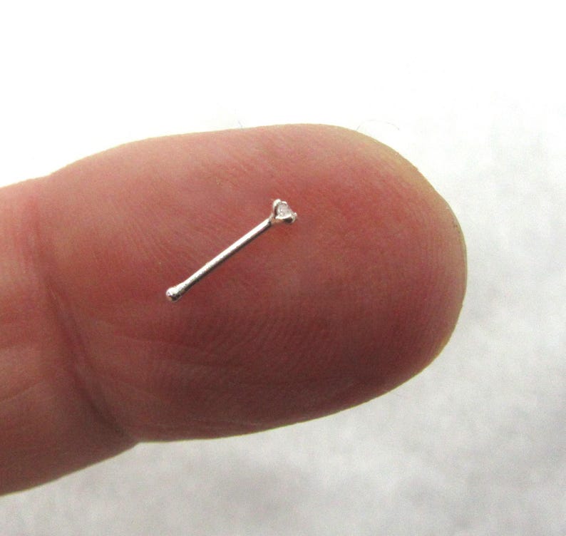 May include: A silver nose ring with a small clear gemstone.