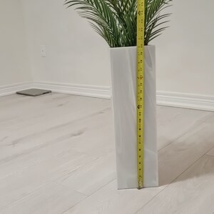 以下が含まれることがあります： テクスチャ加工された表面を持つ白いセラミックの花瓶で、高さ71cm、緑の人工ヤシの木が入っています。