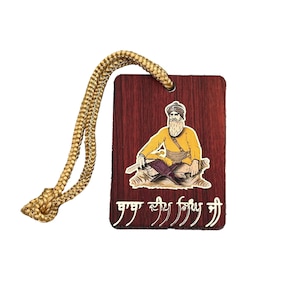 May include: A wooden car charm with a gold rope. The charm features a colorful illustration of a Sikh Guru with a gold background and the text "ਗੁਰੂ ਨਾਨਕ ਸਾਹਿਬ ਜੀ" in gold lettering.