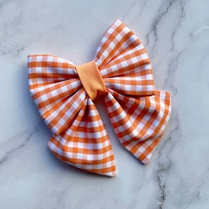 Può includere: Un grande fiocco gingham arancione e bianco con un centro arancione pieno.