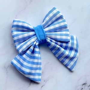 Puede incluir: Un gran lazo azul y blanco de cuadros. El lazo está hecho de tela y tiene un bucle central.
