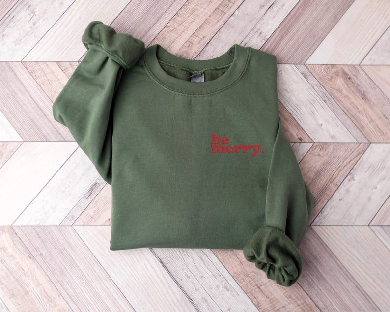 May include: A green sweatshirt with the words "be merry" in red on the front.