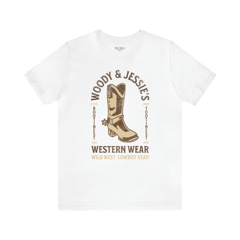 Może przedstawiać: Biała koszulka z brązowym nadrukiem kowbojskiego buta z tekstem "Woody & Jessie's" w k&oacute;łku wok&oacute;ł buta. Tekst "Western Wear" znajduje się pod butem, a tekst "Wild West Cowboy Gear" pod nim.