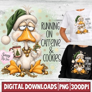 May include: A white duck illustration wearing a green Santa hat, holding a coffee mug and a Christmas tree cookie, with the text RUNNING ON CAFFEINE & COOKIES. The design is shown on a white t-shirt and a black sweatshirt, featuring gold bells.