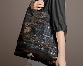 May include: A black tote bag with a colorful image of a waterfall cascading over rocks. The image is surrounded by a dark border.