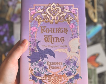 Peut inclure: Un livre violet et rose avec un motif doré sur la couverture. Le titre est "Fourth Wing" et le sous-titre est "The Empyrean Series". Le nom de l'auteur est "Rebecca Yarros".