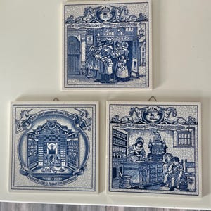 May include: Three square ceramic tiles with blue and white illustrations. The tiles depict scenes of a pharmacy, including people interacting and shelves of medicine. The text on the tiles reads "Burroughs Wellcome Co Pharmacy Scholarship Program".
