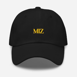 Puede incluir: Una gorra de béisbol negra con el texto MIZ bordado en hilo amarillo en la parte frontal. La gorra cuenta con una corona estructurada, una visera curva y un botón en la parte superior central, presentando un diseño sencillo y claro.