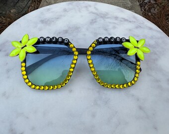 Widespread Panic WWJBD sunglasses. Sturdy black square frame with light grey ombré lenses. Yellow flowers and yellow rhinestones.