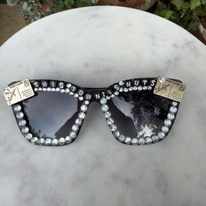 Weit verbreitete Panic Postkarten Sonnenbrille. Schwarze Rahmen, kristallfarbene Strasssteine, 2Postkarten an den Ecken. Sehr detailreich. "Diese Stadt ist verrückt""text."