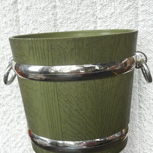 May include: A green plastic ice bucket with a woodgrain pattern and silver trim. The bucket has two handles.