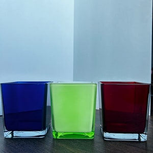 May include: Three square glass candle holders, one blue, one green, and one red.