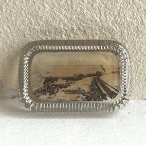 May include: A clear glass ashtray with a silver rim and a black and white photo inside. The photo shows a train track with the text "Above the Clouds, Summit Pines Peak, Colo."