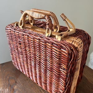 May include: A brown and tan woven wicker basket with a handle. The basket is rectangular and has a woven pattern.