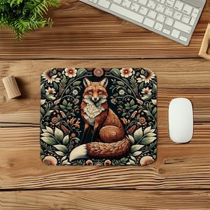 May include: A decorative mousepad featuring a detailed illustration of a fox with orange and white fur, surrounded by floral elements in shades of orange, green, and cream against a dark background. The mousepad is rectangular.