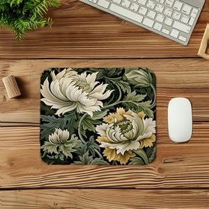 May include: Rectangular mousepad featuring a floral design with large white and yellow flowers and green leaves against a black background. The mousepad is surrounded by a wooden desk, a computer mouse, a keyboard, and a small wooden object.