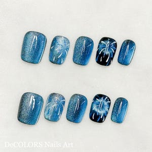 May include: Ten blue and white nail polish designs featuring a firework motif. The nail polish is applied to artificial nails.