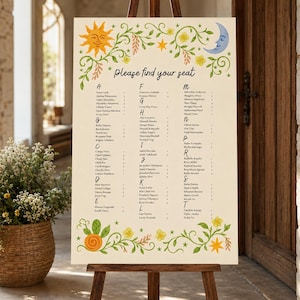 May include: A cream-colored wedding seating chart sign on a wooden easel. The top features a yellow sun, a blue crescent moon, and green vines with yellow flowers. The text reads "Please find your seat" above a list of names organized by letter.