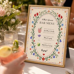 Whimsical floral wedding bar menu sign with colorful folk art border and illustrated drinks, editable Canva template displayed on easel and table settings