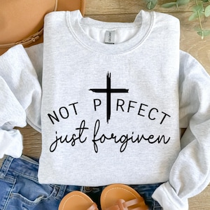 May include: A gray sweatshirt with a black cross and the text "NOT PERFECT just forgiven".