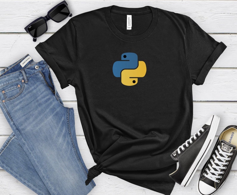 May include: Black t-shirt with a yellow and blue Python logo. The t-shirt is on a white wooden surface with a pair of blue jeans, sunglasses, and black sneakers.
