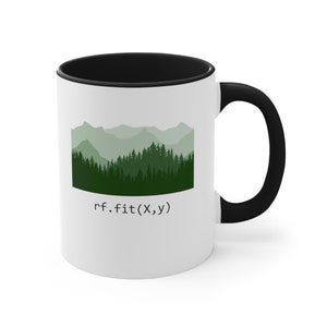 May include: White ceramic mug with a black interior and handle. The mug features a green and white mountain and forest graphic with the text "rf.fit(X,y)".