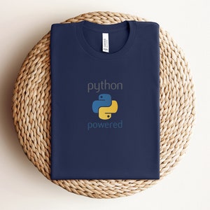 Pode incluir: Uma camiseta azul marinho com o texto "python powered" e um logotipo de pit&atilde;o amarelo e azul.