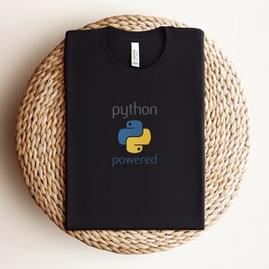 Pode incluir: Camiseta preta com o texto "python powered" e um logotipo de pit&atilde;o amarelo e azul.