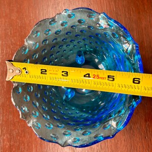 May include: A blue glass bowl with a scalloped edge and a textured surface. The bowl is approximately 4.25 inches in diameter.