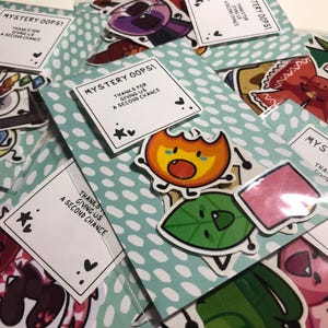 May include: A set of colorful stickers featuring cartoon characters with the text "Mystery Oops! Thanks for giving us a second chance." The stickers are packaged in clear plastic bags.