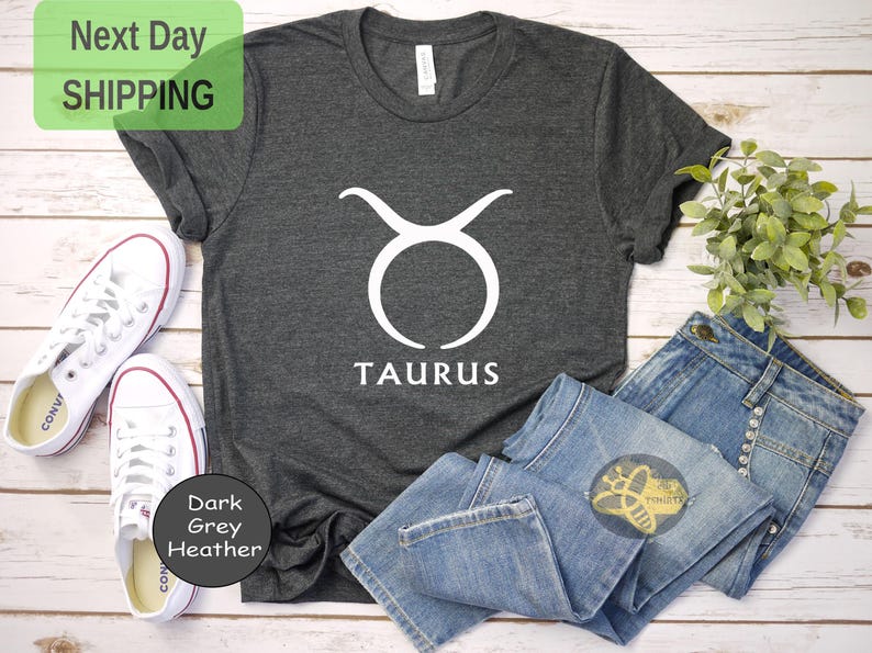 May include: Dark grey heather t-shirt with a white Taurus zodiac symbol and the word "TAURUS" printed on the front.